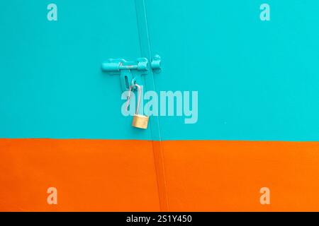 Metal door with Latch and a open Lock. Stainless steel padlock on a green and orange back ground. Home safety door lock. Stock Photo