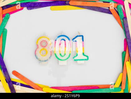 Candles in shape of the number 801 in popsicle colorful sticks frame isolated on white background Stock Photo