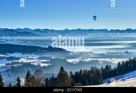 hot-air ballon flying over the panoramic landscape of the snowy and misty Bregenz Forest Mountains , Vorarlberg, Austria Stock Photo