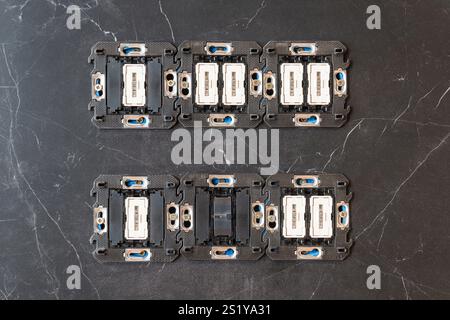 Electrical switch mechanisms mounted in two rows on the porcelain tile wall Stock Photo