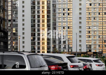 Urban building facade with parked cars. Modern residential block featuring plenty of windows on a concrete exterior. Contemporary architecture showcas Stock Photo