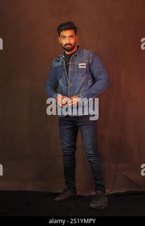 An indian male model posing in denim jacket and jeans against grey background full length pictures Stock Photo