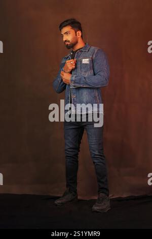 An indian male model posing in denim jacket and jeans against grey background full length pictures Stock Photo