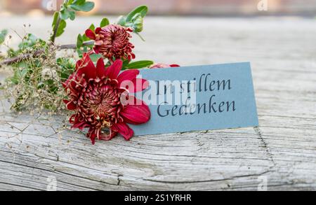 Condolence card with dark red chrysanthemums and German text: In silent memory Stock Photo