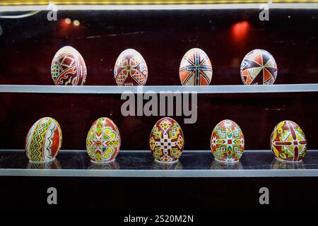 A row of colorful eggs are displayed on a shelf. The eggs are arranged in a way that they look like they are sitting on top of each other. The eggs ar Stock Photo
