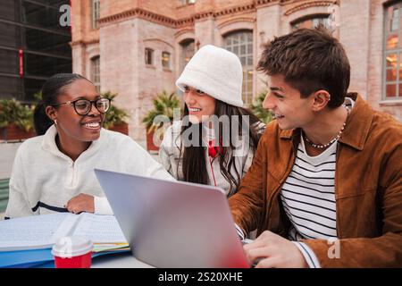 Group of Diverse Students Collaborating on a Laptop in an Outdoor Study Session, Engaging in Creative Discussion and Sharing Ideas, Fostering Teamwork and Friendship Among Peers. Three Classmates. High quality photo Stock Photo