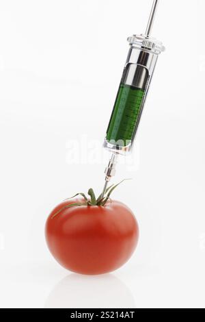 A green liquid is injected into a tomato. Symbolic photo for Gentomatoes. Austria Stock Photo