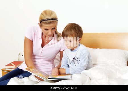 A mother and child in bed reading stories. Austria Stock Photo