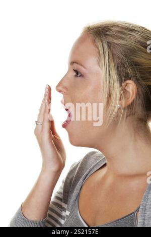 A young woman holds her hand over her mouth while yawning. Tiredness and lack of sleep Stock Photo