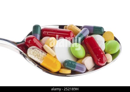 Many different coloured tablets on a spoon. Abuse of medication. against a white background. Austria Stock Photo