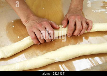Woman rolls out dough on the table with her hands Stock Photo