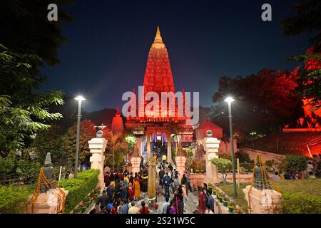 The Mahabodhi Temple complex illuminated in red in the early evening, with large crowds making their way to the sanctum sanctorum in the main tower Stock Photo