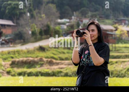 Woman photographer with big backpack taking photo of mountains and blue lake. Travel and hobby concept. Young woman with camera against mountains Stock Photo