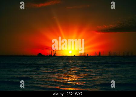 Nature's fiery masterpiece. A breathtaking sunset paints the sky with vibrant hues, casting its glow over the tranquil sea. Stock Photo