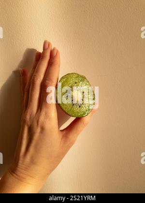 Hand holding an open kiwi in a soft warm light Stock Photo