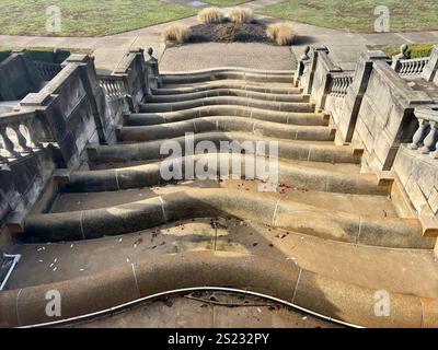 Top-down view of curved concrete fountain steps with scattered petals Stock Photo