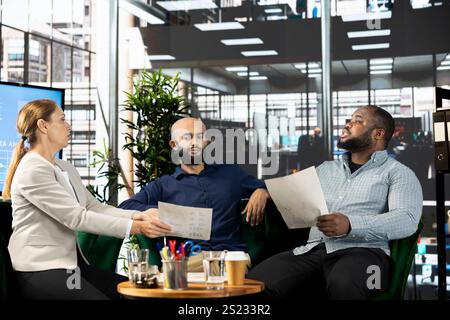 Diverse businesspeople in startup workplace looking through financial business documents. Workers in office checking accounting figures, finishing tedious paperwork, discussing about data Stock Photo