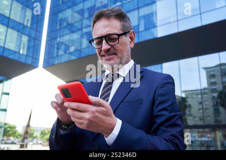 Mature businessman using mobile phone sending messages smiling. Stock Photo