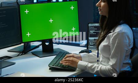 System administrator in data center installing software on green screen computer, troubleshooting issues. IT expert uses mockup PC in server hub, establishing performance benchmarks, camera A Stock Photo