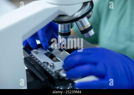 Unrecognizable female doctor in clinic focused on scientific study using microscope Stock Photo