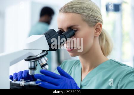 Female doctor in clinic using modern microscope and equipment for concentrated study Stock Photo