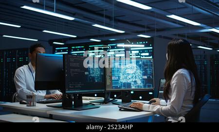 Technicians coworkers using AI tech on computer to do checkup in server room. Teamworking colleagues in data center using artificial intelligence technology to process datasets for training, camera B Stock Photo