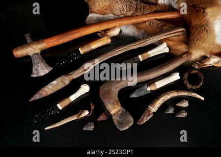 Stone Age Tools with Knives and Animal Fur on black Background Stock Photo