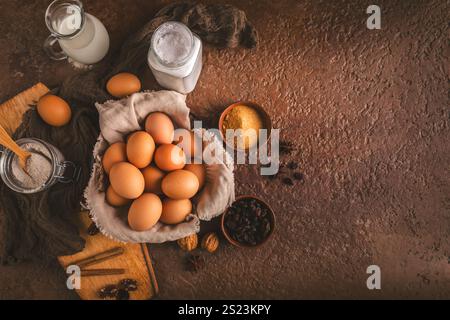Organic brown eggs with assorted baking ingredients and kitchen utensils in brown tone Stock Photo