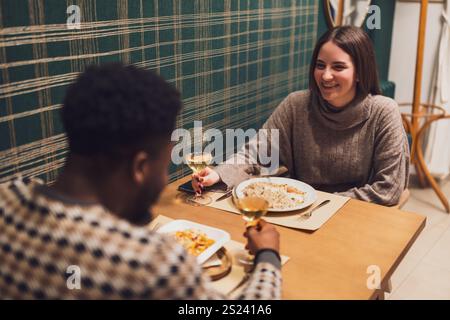 Two friends are having dinner at restaurant. They are sitting, talking and enjoying time together. Stock Photo