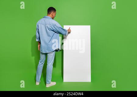 Full body photo of young man using huge phone touchscreen surfing in social media isolated on green color background Stock Photo