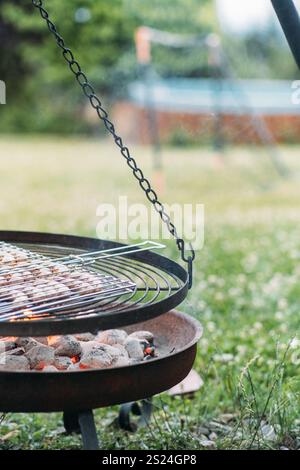 Enjoying eco friendly grilling with low waste cooking methods over a natural fire pit in a tranquil outdoor setting during a sunny afternoon Stock Photo