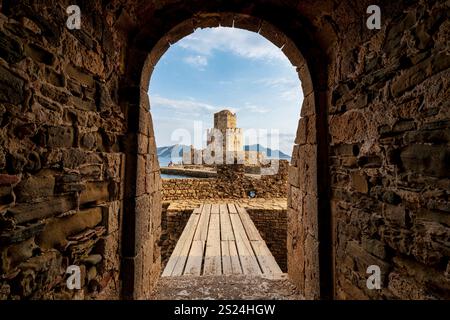 The iconic Bourtzi Tower at Methoni Fortress, viewed through a stone archway with a wooden bridge leading toward the historic structure. Stock Photo