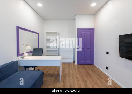 Bright and inviting space featuring a modern sofa, desk, cabinetry, and colorful decorative elements, offering a cheerful and functional ambiance. Stock Photo