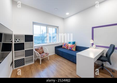 Bright and inviting space featuring a modern sofa, desk, cabinetry, and colorful decorative elements, offering a cheerful and functional ambiance. Mod Stock Photo