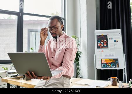 A young African American man focuses on his laptop, brainstorming ideas in an inspiring setting. Stock Photo