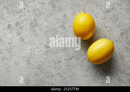 two fresh lemons on grey kitchen table background, top view Stock Photo