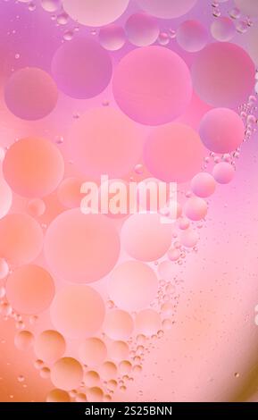 Abstract macro photo of oil droplets suspended in water with warm orange and pink hues. Oil and water bubbles macro photo. Stock Photo