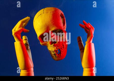 Human skull and mannequin hands on blue background Stock Photo