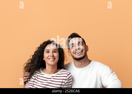 Dreamy Young Arab Couple Sitting On Floor And Looking At Copy Space Stock Photo