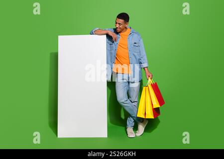 Full body photo curious young man go shopping using huge smartphone to shop online isolated on green color background Stock Photo