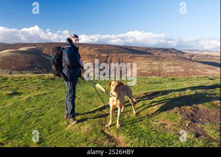 Walker and Red Fox Labrador on the summit of Lose Hill Ward's Place with Kinder Scout in the distance, Peak District National Park Stock Photo