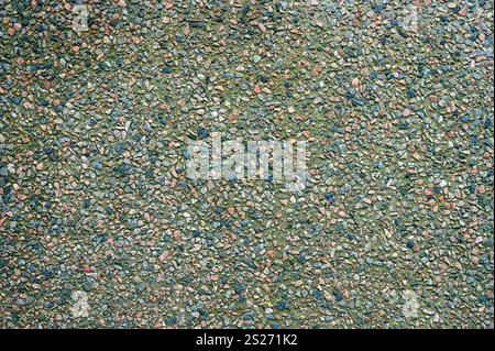 A close view of a textured surface made of small, multicolored pebbles arranged on the ground, showcasing an array of natural hues and patterns, perfe Stock Photo