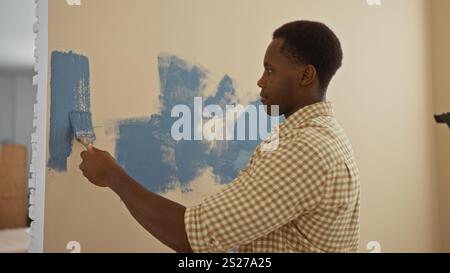 Young man painting wall in living room of new home with blue color creating refreshing interior atmosphere during renovation project Stock Photo