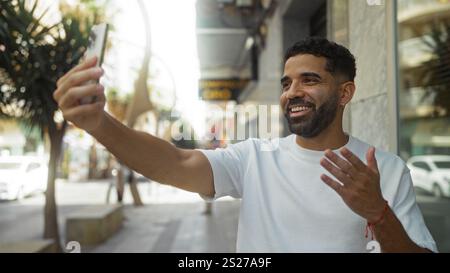 Young man having a videcall smiling outdoors in a city street Stock Photo