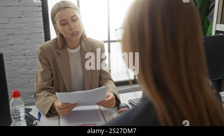 Women discussing business documents in modern office with focus on teamwork and collaboration. Stock Photo