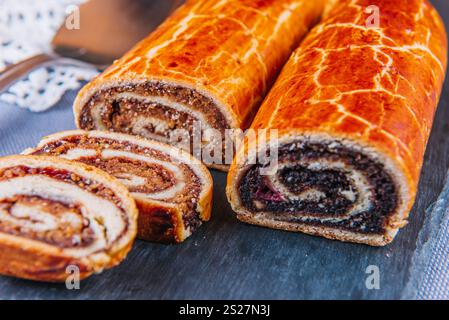 Traditional Hungarian Christmas cookies with poppy seed and walnut on a black cutting board. Stock Photo