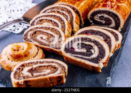 Traditional Hungarian Christmas cookies with poppy seed and walnut on a black cutting board. Stock Photo