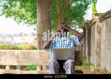 Young cheerful black man using mobile phone and laptop computer. Modern lifestyle Stock Photo