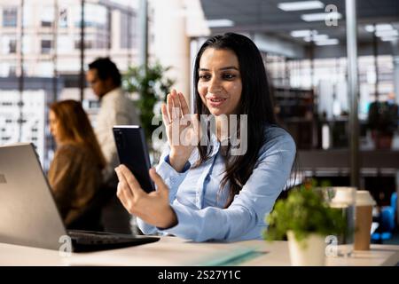Professional indian worker leads a teleconference with team members, discussing project details and strategic objectives. Virtual meeting ensures efficient business communication across locations. Stock Photo