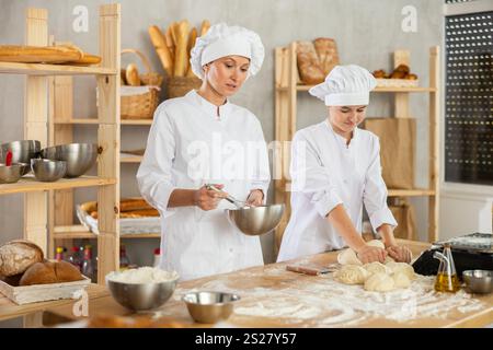 Female bakers in uniform preparing gray dough Stock Photo